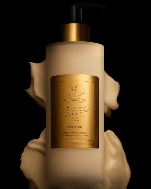Luksusowa butelka balsamu do rąk i ciała Creed Aventus Hand & Body Lotion z matowego szkła, ozdobiona złotą etykietą z logo Creed i pompą dozującą. Produkt otoczony kremową pianą, sfotografowany na czarnym tle, emanuje elegancją i wyrafinowaniem