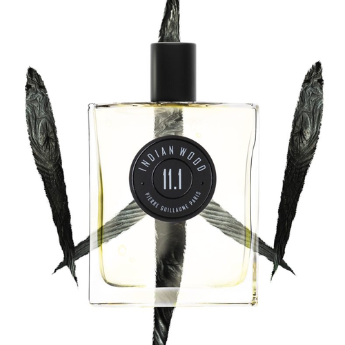 Flakon perfum Pierre Guillaume Indian Wood 11.1 – prostokątna, przezroczysta butelka z jasnożółtym płynem i czarną, matową zakrętką. Na froncie widoczna jest okrągła etykieta z nazwą zapachu i numerem. W tle znajdują się trzy czarne pióra ułożone w kształt trójramiennej gwiazdy, nadające kompozycji graficznej egzotyczny i tajemniczy charakter