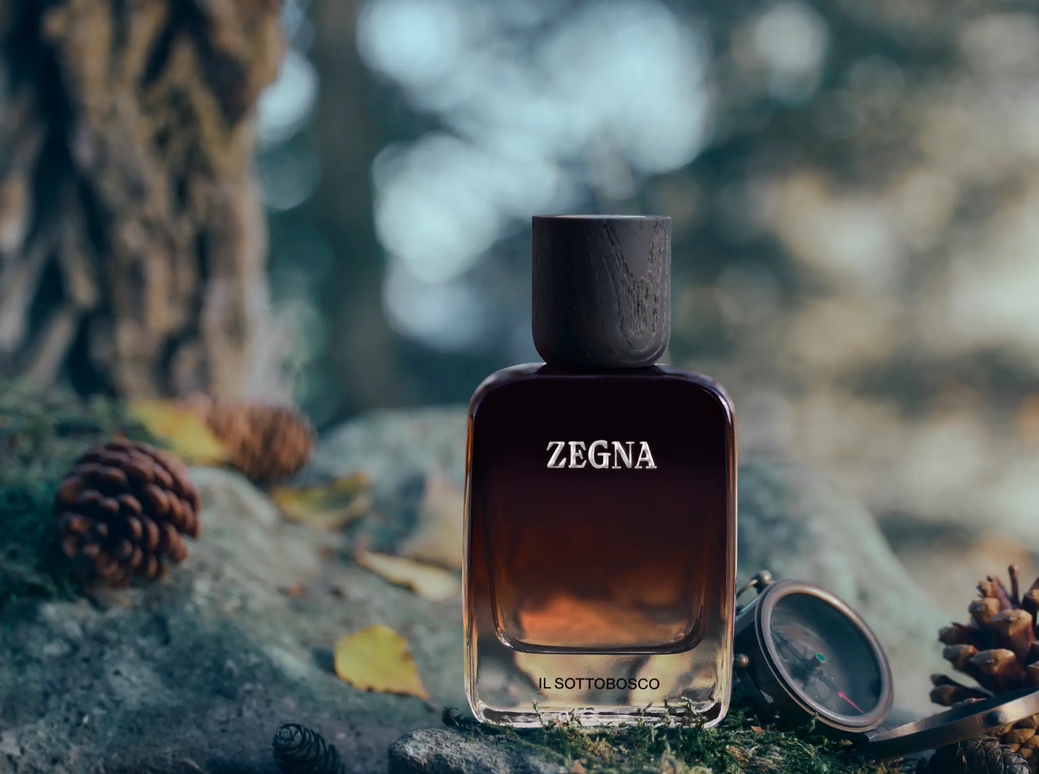 Flakon perfum Zegna Il Sottobosco na tle inspirowanym leśnym poszyciem, wilgotną ziemią i liśćmi. Kompozycja podkreśla drzewno-przyprawowy, ziemisty charakter zapachu.